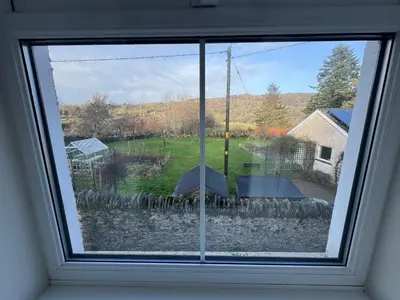 a window with a view of a yard with umbrellas at Cozy cottage at the base of Sale and Ling Fell in Embleton