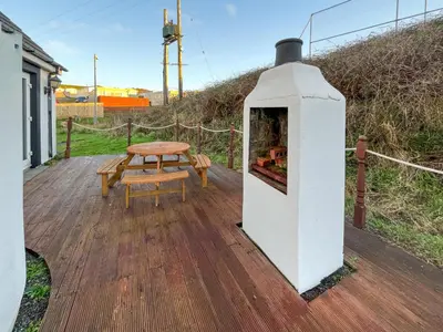 a wooden deck with a table and a fireplace at Graeme-An-Taoiseach Uk50061 in Stranraer