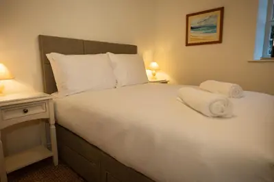 a bedroom with a large bed with white sheets and pillows at River View Cottages in Annan