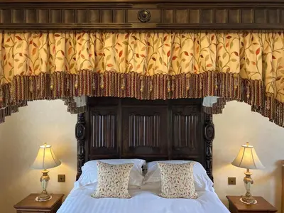 a canopy bed with a wooden headboard with curtains at Scale Hill Hotel in Loweswater