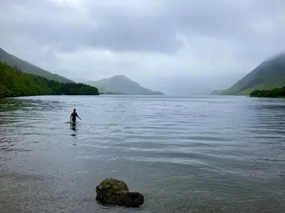 a man is standing in the water in a river at Scale Hill Hotel in Loweswater