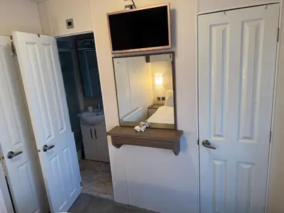 a bathroom with a mirror and a tv on a wall at Turnberry Holiday Park Amazing Sea View in Girvan
