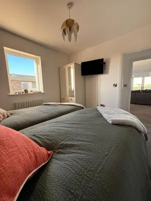 a bedroom with two beds and a flat screen tv at Black Dub Cottage in Allonby