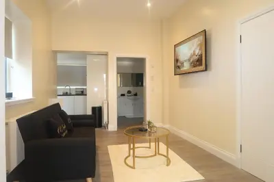 a living room with a black couch and a table at Luxury one bedroom apartment in Dumfries