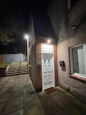 a white door on the side of a building at night at Luxury one bedroom apartment in Dumfries