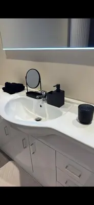 a bathroom counter with a white sink and a mirror at Luxury one bedroom apartment in Dumfries