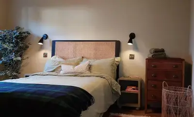 a bedroom with a bed and a dresser and lights at Cosy Cottage in Charming Village Close to Beach - Pass the Keys in Kirkbean