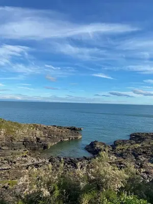 a view of the ocean from a rocky shore at Cosy Cottage in Charming Village Close to Beach - Pass the Keys in Kirkbean