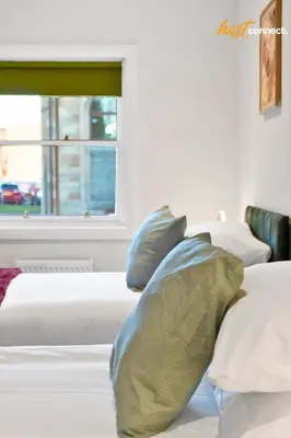 a bedroom with two beds with pillows and a window at 2 Bed Flat in Airdrie I Sleeps 4 I Parking in Moffat