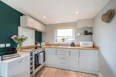 a kitchen with white cabinets and a window at 1 Bed in Gatehouse Of Fleet oc-t34445 in Gatehouse of Fleet