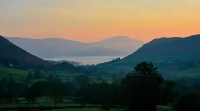 a misty valley with mountains in the distance at sunset at High Snab Cottage Newlands Valley in Keswick