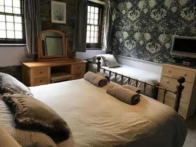 a bedroom with two beds and a tv and a mirror at 3 Millbeck Cottage in Keswick