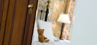 a teddy bear sitting on a bed next to a lamp at Burnside B&B in Keswick