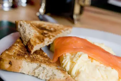 a plate of food with a sandwich and a tomato at Burnside B&B in Keswick