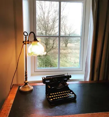 an old typewriter sitting on a table next to a window at Keeper's Cottage at Slogarie Estate in Castle Douglas
