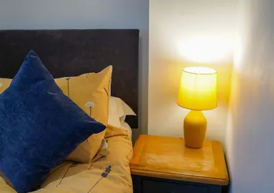 a bed with a blue pillow and a lamp on a table at Coppet Cove - 2 Bedroom Apartment - Saundersfoot in Moffat