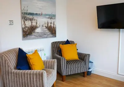 two chairs with yellow pillows in a living room at Coppet Cove - 2 Bedroom Apartment - Saundersfoot in Moffat
