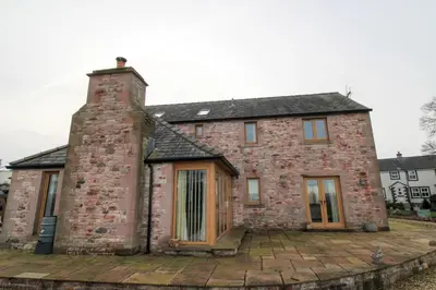 an old brick house with a chimney on a patio at Mindrum, Skelton a spacious and characterful house close to Penrith & Ullswater in Skelton