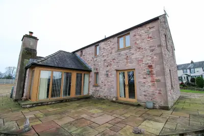 an old brick house with a patio in front of it at Mindrum, Skelton a spacious and characterful house close to Penrith & Ullswater in Skelton