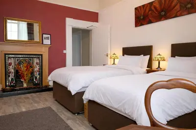 two beds in a hotel room with a fireplace at The Manor House in Peel