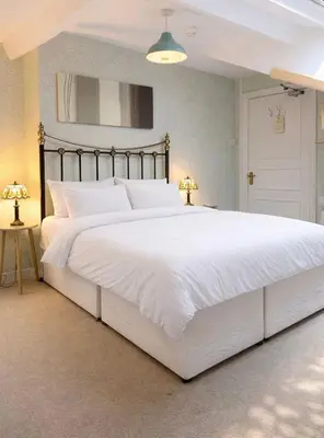 a large white bed in a bedroom with two lamps at The Manor House in Peel