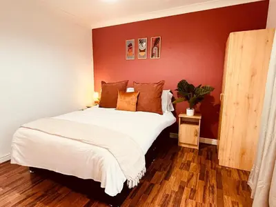 a bedroom with a large white bed with red walls at 3-Bedroom house near Manchester City Centre in Moffat