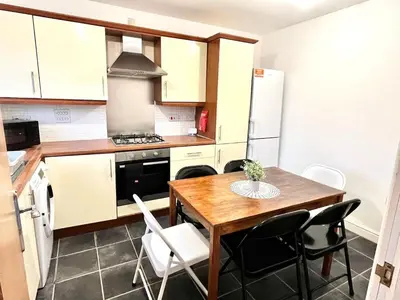 a small kitchen with a wooden table and chairs at 3-Bedroom house near Manchester City Centre in Moffat