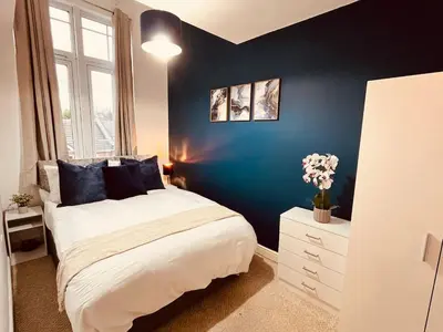 a bedroom with a bed and a blue wall at 3-Bedroom house near Manchester City Centre in Moffat