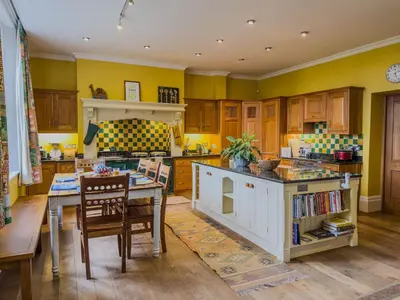 a kitchen with yellow walls and a table and chairs at Eden Mount, Wetheral, characteful, spacious home overlooking village green, close to M6 in Wetheral