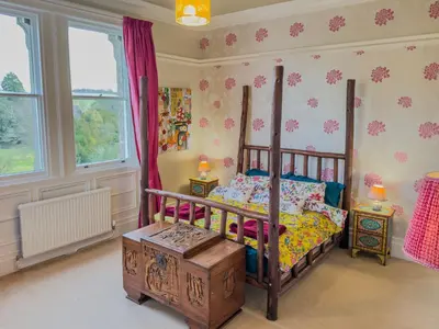 a bedroom with a bed and a table and windows at Eden Mount, Wetheral, characteful, spacious home overlooking village green, close to M6 in Wetheral