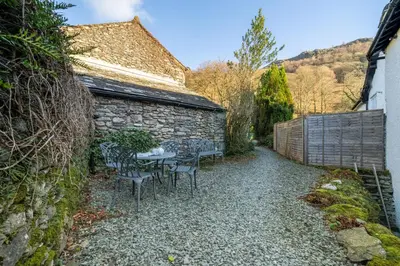 a patio with chairs and a table and a building at Ben Place Cottage - Grasmere in Grasmere