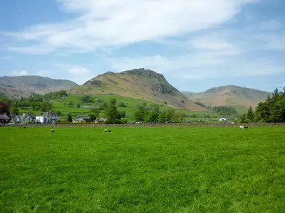 a field of green grass with mountains in the background at Ben Place Cottage - Grasmere in Grasmere