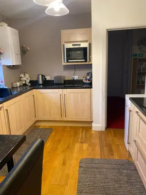 a kitchen with wooden cabinets and a microwave at Gramhor House in Dumfries