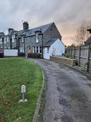 a house with a road in front of a yard at Cosy Cottage in Moffat, South Scotland in Moffat