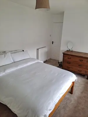 a bedroom with a large white bed and a wooden dresser at Cosy Cottage in Moffat, South Scotland in Moffat