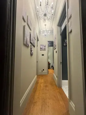 a hallway with a chandelier and wooden floors at West London Boutique Apartment in Moffat