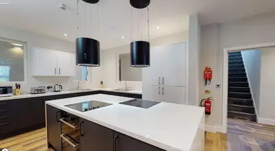 a kitchen with white cabinets and a white counter top at Modern En-suite Room in Moffat