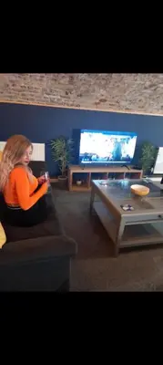 a woman sitting on a couch in a living room at Town Centre Apartment in Gatehouse of Fleet