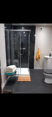 a bathroom with a shower with a person taking a picture at Town Centre Apartment in Gatehouse of Fleet