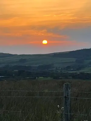 a sunset over a field with a fence at West Cumbria static caravan in Workington