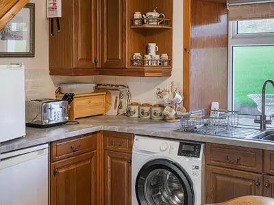 a kitchen with a washing machine and a sink at East Challoch Farm Dairy Cottage in Stranraer