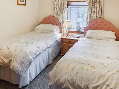 two beds in a bedroom next to a window at East Challoch Farm Dairy Cottage in Stranraer