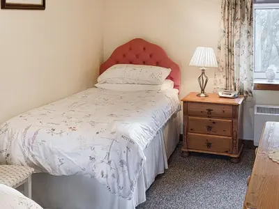 a bedroom with a bed with a red headboard and a table at East Challoch Farm Dairy Cottage in Stranraer