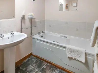 a white bathroom with a tub and a sink at East Challoch Farm Dairy Cottage in Stranraer