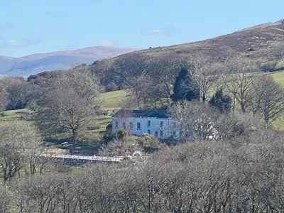 a house in the middle of a hill with trees at Highside farm in Embleton