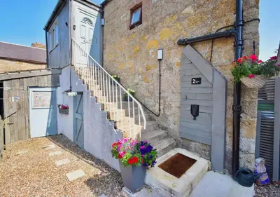 a set of stairs leading up to a building with flowers at Peaceful Village Flat 2 Bedrooms in Douglas