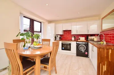 a kitchen with a wooden table with chairs and a kitchen with a dishwasher at Peaceful Village Flat 2 Bedrooms in Douglas