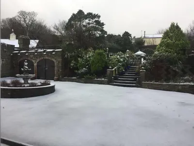 a courtyard with a stone building with a fountain and stairs at Ravenscliffe Lodge in Douglas