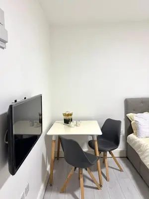 a table and two chairs and a tv in a room at Cozy Golders Green Studio Flat in Moffat