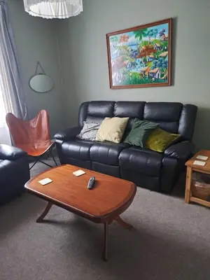 a living room with a black leather couch and a coffee table at Brewery house in Newton Stewart